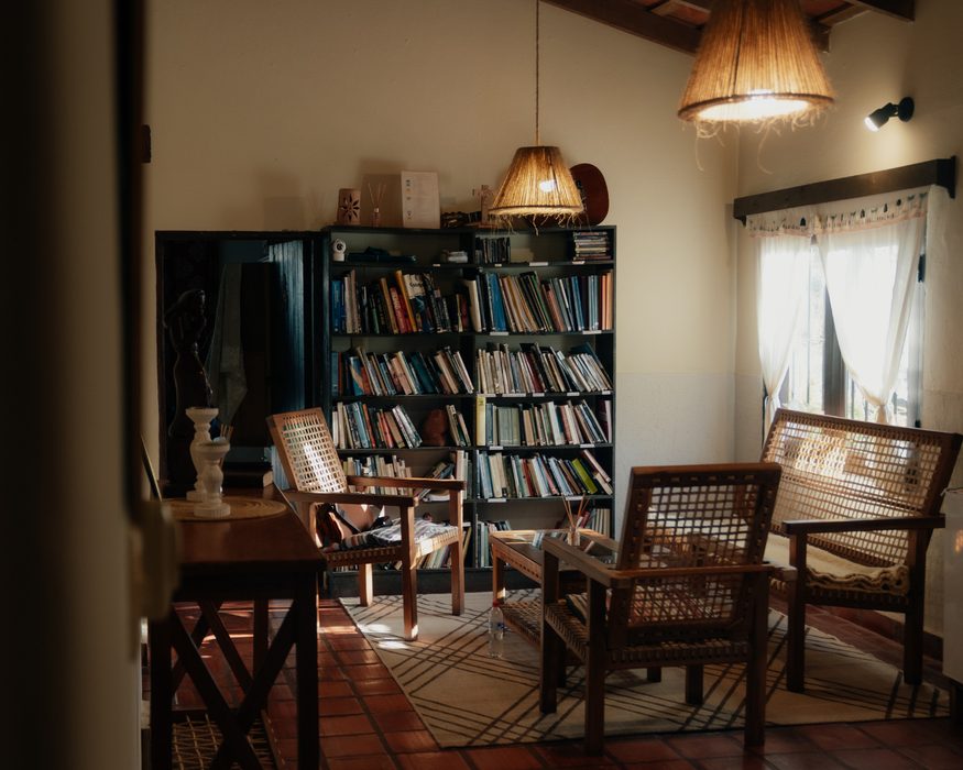 Sala de leitura com poltronas de vime e estante de livros
